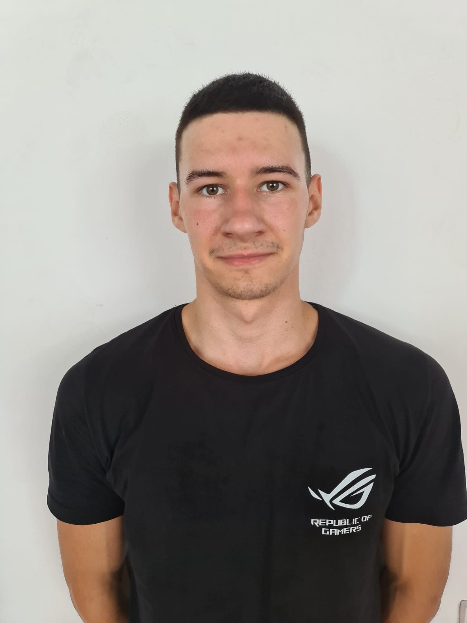 Portrait of a young man wearing a black Republic of Gamers t-shirt against a white background.
